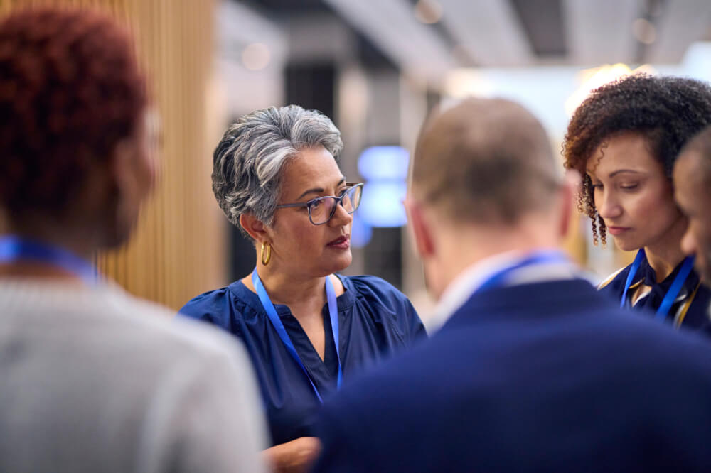 A female CEO is facilitating an open dialogue with her peers. Real progress happens when people feel safe to share openly.