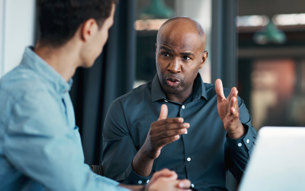 A senior manager is receiving negative feedback open-mindedly. Welcoming feedback demonstrates a commitment to growth and integrity.